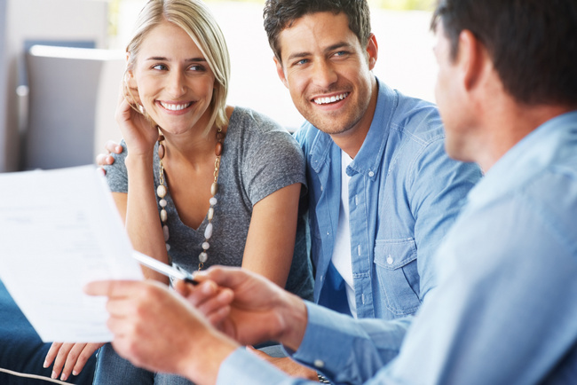 Portrait of a happy young couple discussing investment plans with a financial planner - Indoor